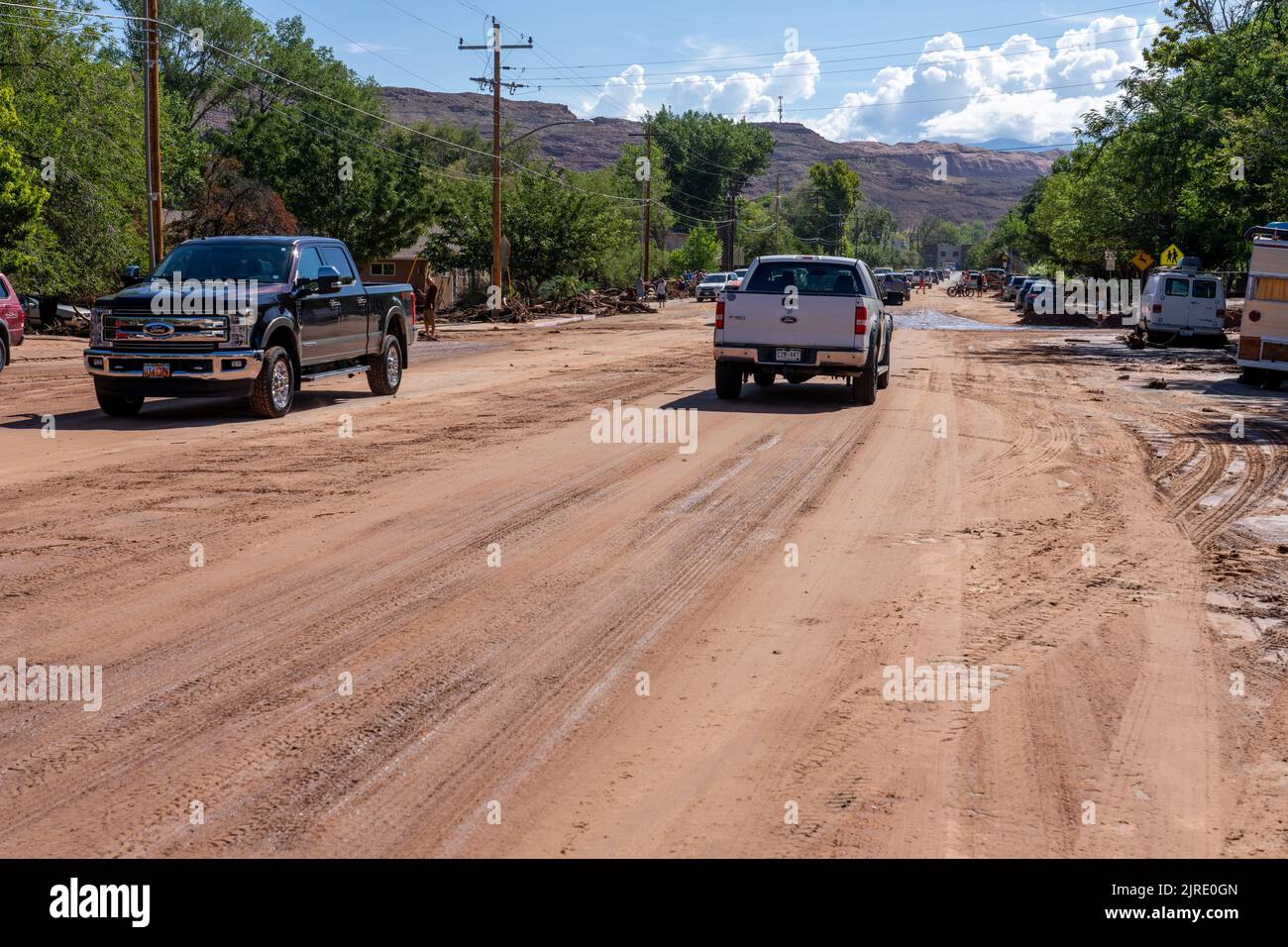 Fahrzeuge fahren auf einer Straße, die in der Nacht zuvor in Moab, Utah, von Schlamm und Trümmern bedeckt war. Stockfoto