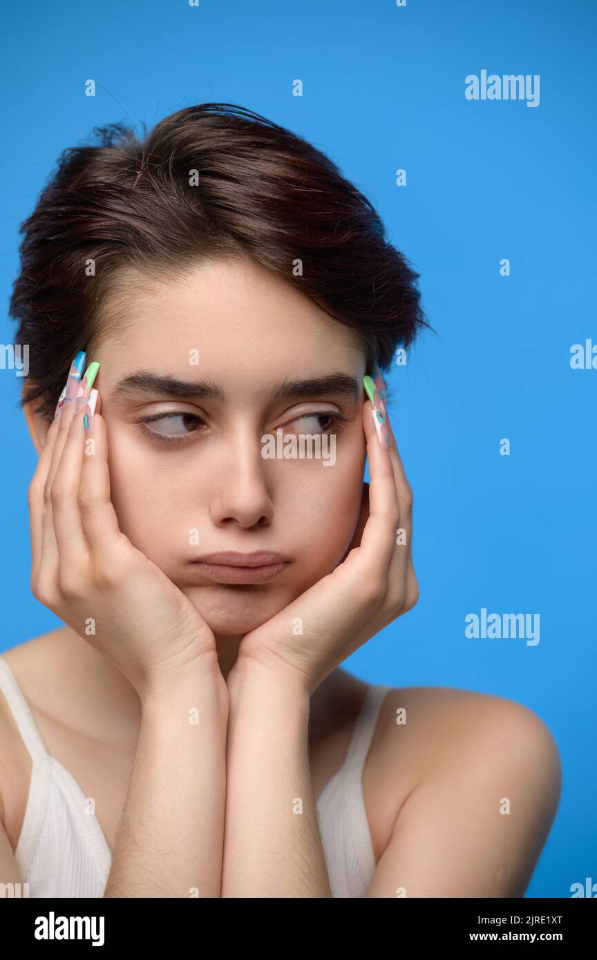 Depressive gelangweilte Teenager Mädchen auf blauem Hintergrund Stockfoto