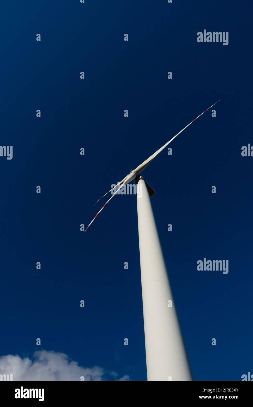 Weiße Rotorblätter einer Windturbine vor dem Hintergrund eines marineblauen Himmels. Erneuerbare Energiequellen im Dekarbonisierungsprozess. Stockfoto