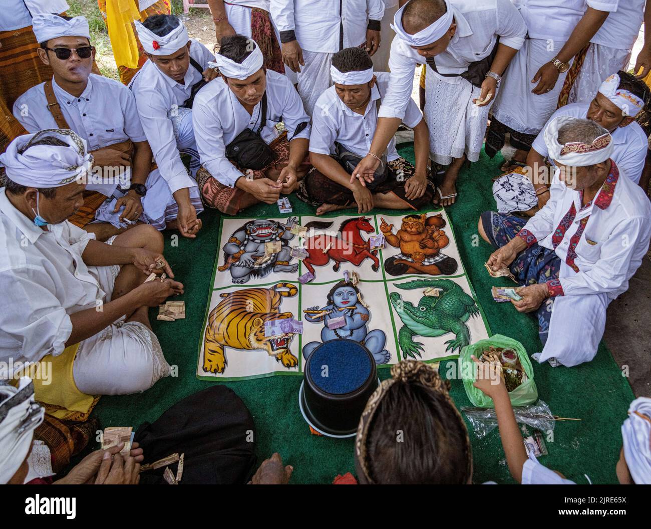 Männer spielen am Galungan Day in Bali mit Geld auf einem Brettspiel. Stockfoto