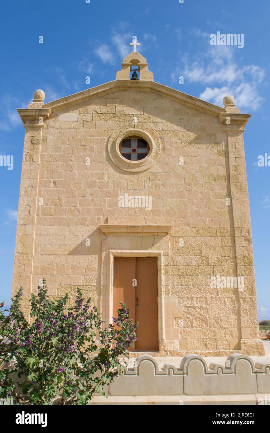 Die aus Kalkstein isolierte historische katholische Kapelle von Saint Dimitri, in der Landschaft von Gharb, Gozo, Malta. An einem bewölkten Frühlingstag, mit blauem Himmel. Stockfoto