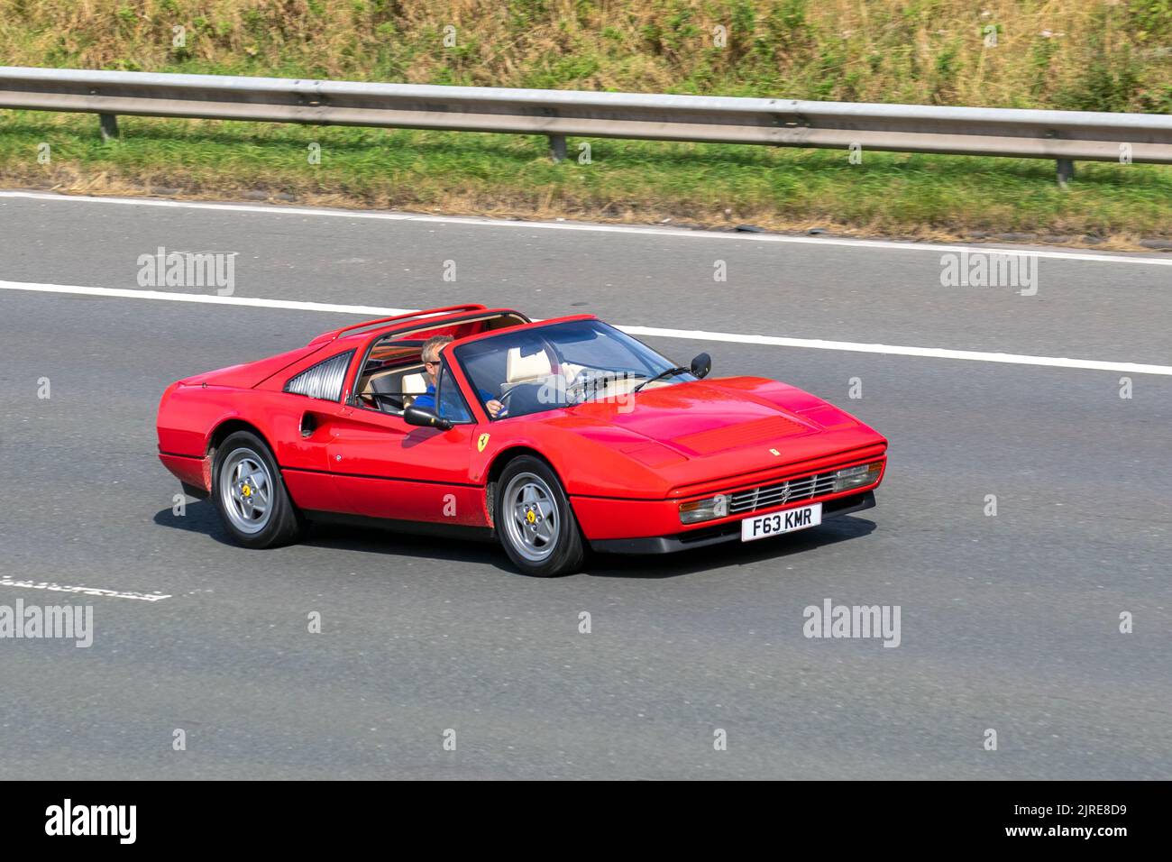 1989, 80s, achtziger Jahre Rot, Rosso Corsa FERRARI 328, Mittelmotor V8, zweisitzige Keilprofil-Sportwagen 3185cc Benzin Italienisch, Targa Roadster; sich bewegend, gefahren, in Bewegung, Anfahrt auf der Autobahn M6, Großbritannien Stockfoto