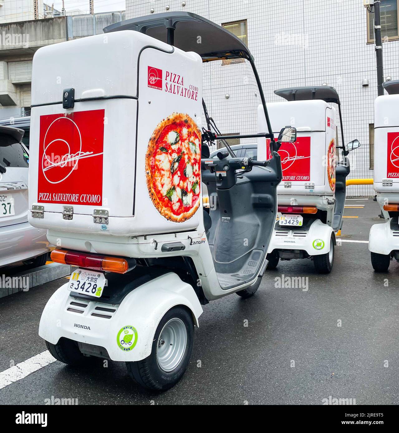 Ein Rückbild von drei 3 Wheel Mobility Scooter Balance Delivery Motorrädern für Pizza Salvatore mit Dächern auf einem Parkplatz geparkt. Stockfoto