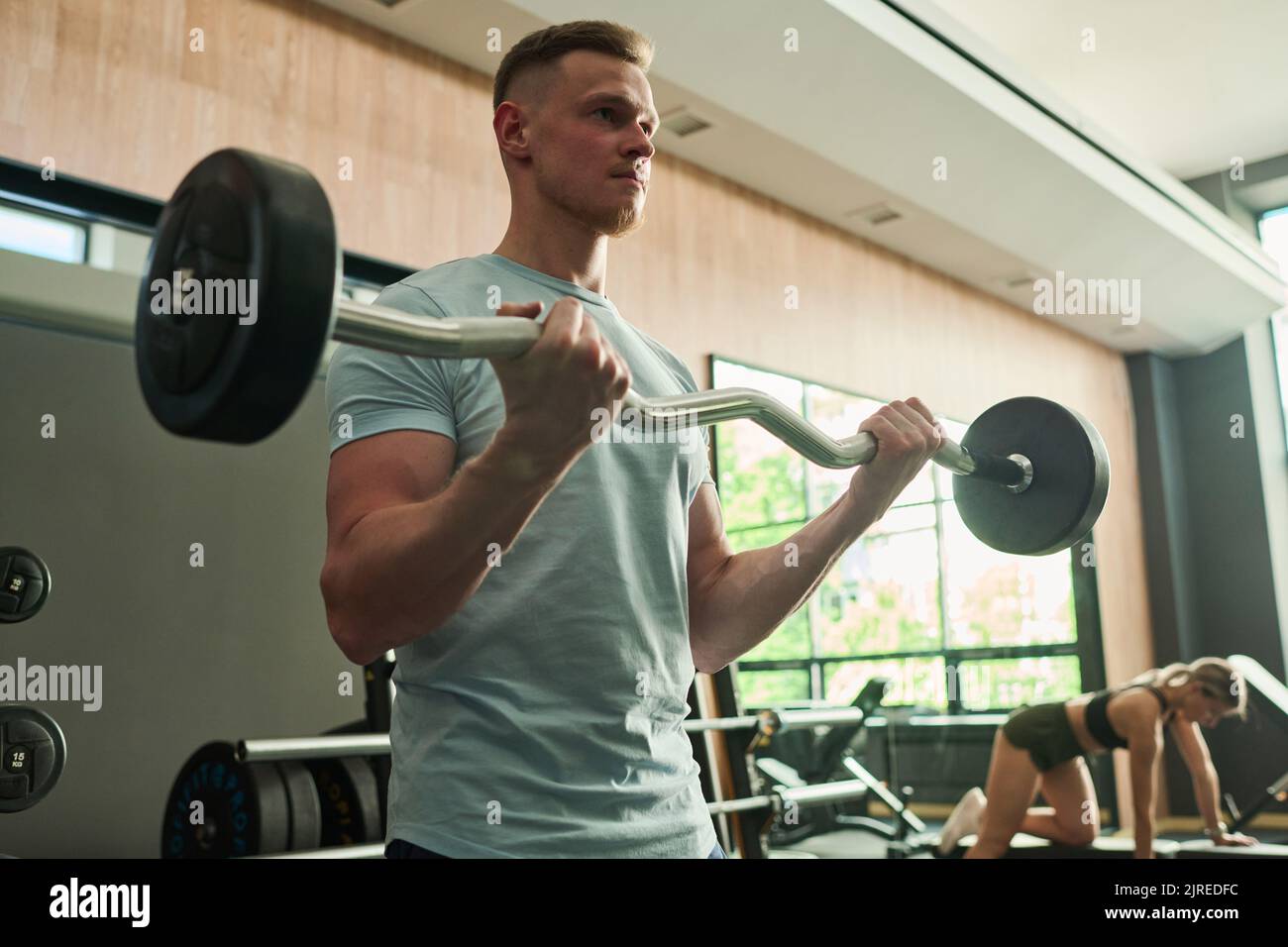 Junger Mann beim Hanteln während seines Sporttrainings im Fitnessstudio Stockfoto