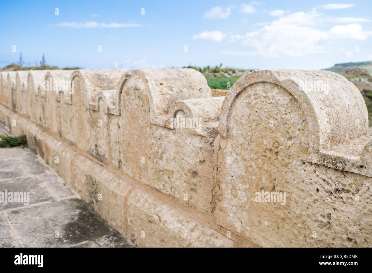 Ein Kalksteinzaun oder eine Grenze, die mit kleinen und großen Steinbögen um die St. Dimitri-Kapelle im ländlichen Dorf Gharb, Gozo, Malta, geschmückt ist Stockfoto