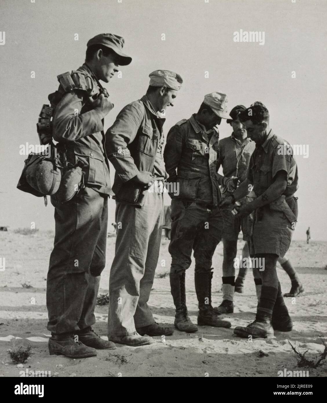 Ein Vintage-Foto um 1942, das britische Soldaten zeigt, die deutsche Kriegsgefangene der deutschen 90. Light Division Afrika korps nach ihrer Gefangennahme in El Alamein Ägypten durchsucht haben Stockfoto
