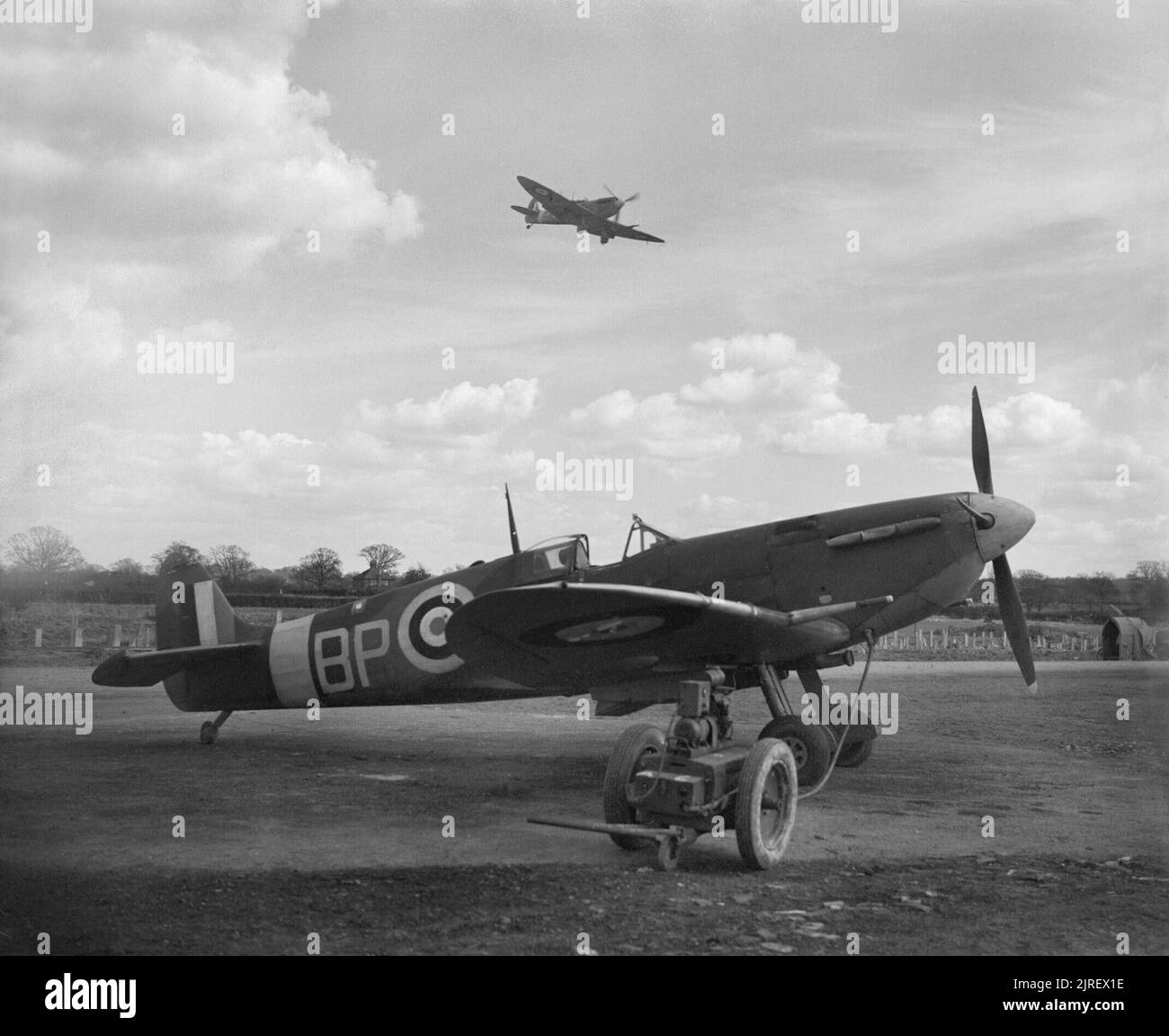 Royal Air Force Fighter Command, 1939-1945. Supermarine Spitfire Mark VB, No 457 Squadron RAAF Rückkehr in Redhill, Surrey, nach einer Schleife über nördlichen Frankreich, während eine zweite Staffel Flugzeuge steht in der Zerstreuung, in einen Trolley Druckspeicher bei Bereitschaft angeschlossen. Stockfoto