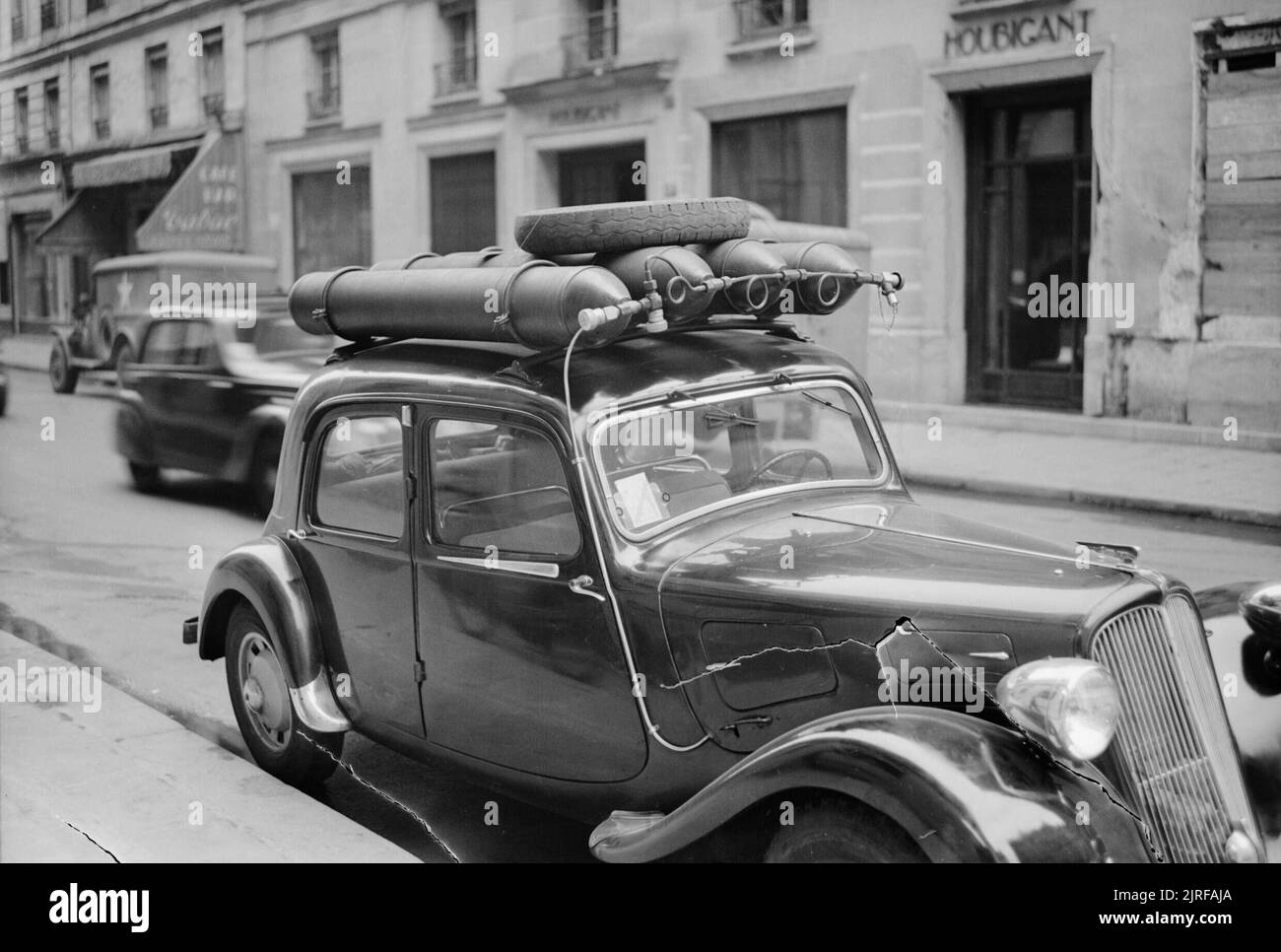 Paris, Spring 1945 - Alltag in Paris, Frankreich, 1945 Ein Blick auf die Pariser Straße und zeigt ein Auto, das umgebaut wurde auf Gas laufen zu lassen, anstatt Benzin. Es gibt vier Gasflaschen auf das Dach des Autos angebracht, und eine kleine Tube läuft ab der Seite und unter der Motorhaube. Stockfoto