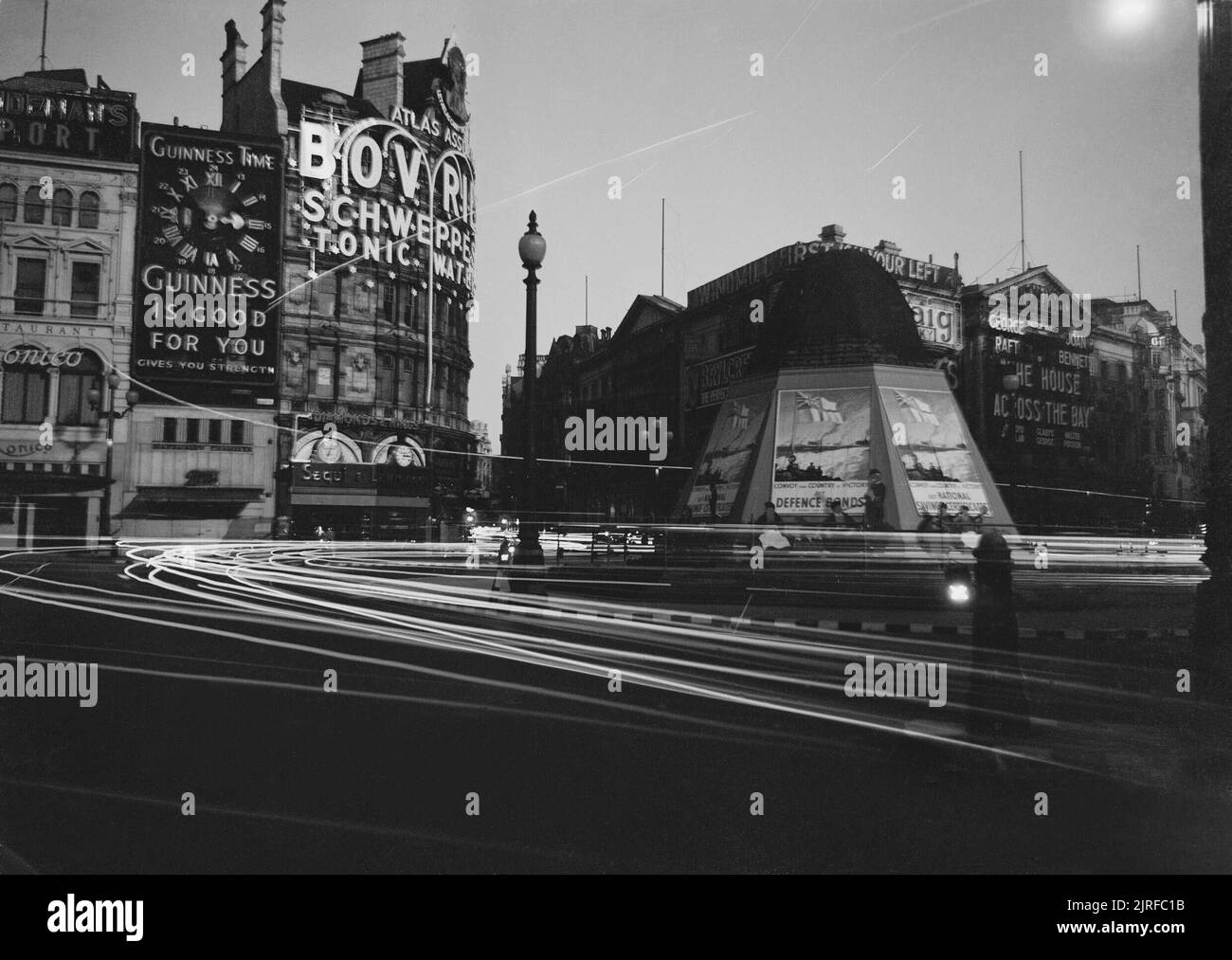 Die Scheinwerfer der Autos streifen durch die Dunkelheit, wie Sie rund um den Piccadilly Circus in London, 1940. Die Scheinwerfer der Autos streifen durch die Dunkelheit, wie Sie rund um den Piccadilly Circus in London reisen. Mehrere Fußgänger sind nur sichtbar. Ein sand-Eingesackt und Zugenagelten Eros können auch gesehen werden. Stockfoto