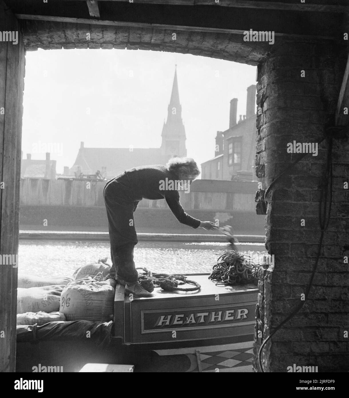 Frauen laufen ein Boot - Leben an Bord der Kanal Barge heather Bell', 1942 Bei der Ankunft in das Lager, in dem sich das Schiff entladen werden soll, Miss März verstaut werden, die oberen Saiten, die die Tücher in der Nähe der Mehl an Ort und Stelle während der Durchfahrt gehalten haben. Stockfoto