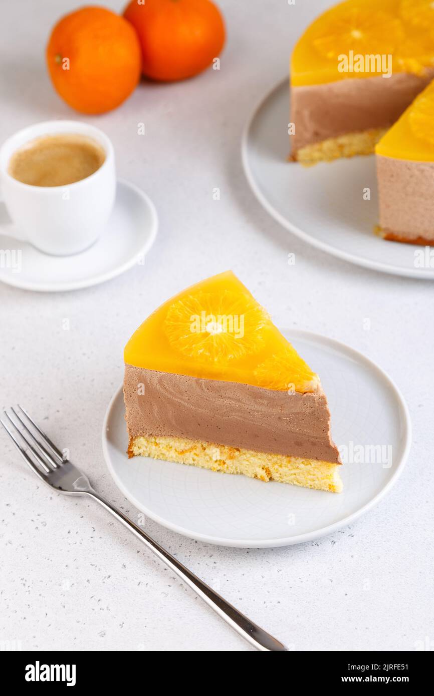 Schokoladen-Orange-Mousse-Kuchen mit Biskuitboden, Gelee und Orangenkreisen. Ein Stück hausgemachter Käsekuchen und eine Tasse Kaffee. Traditionelles Dessert Stockfoto