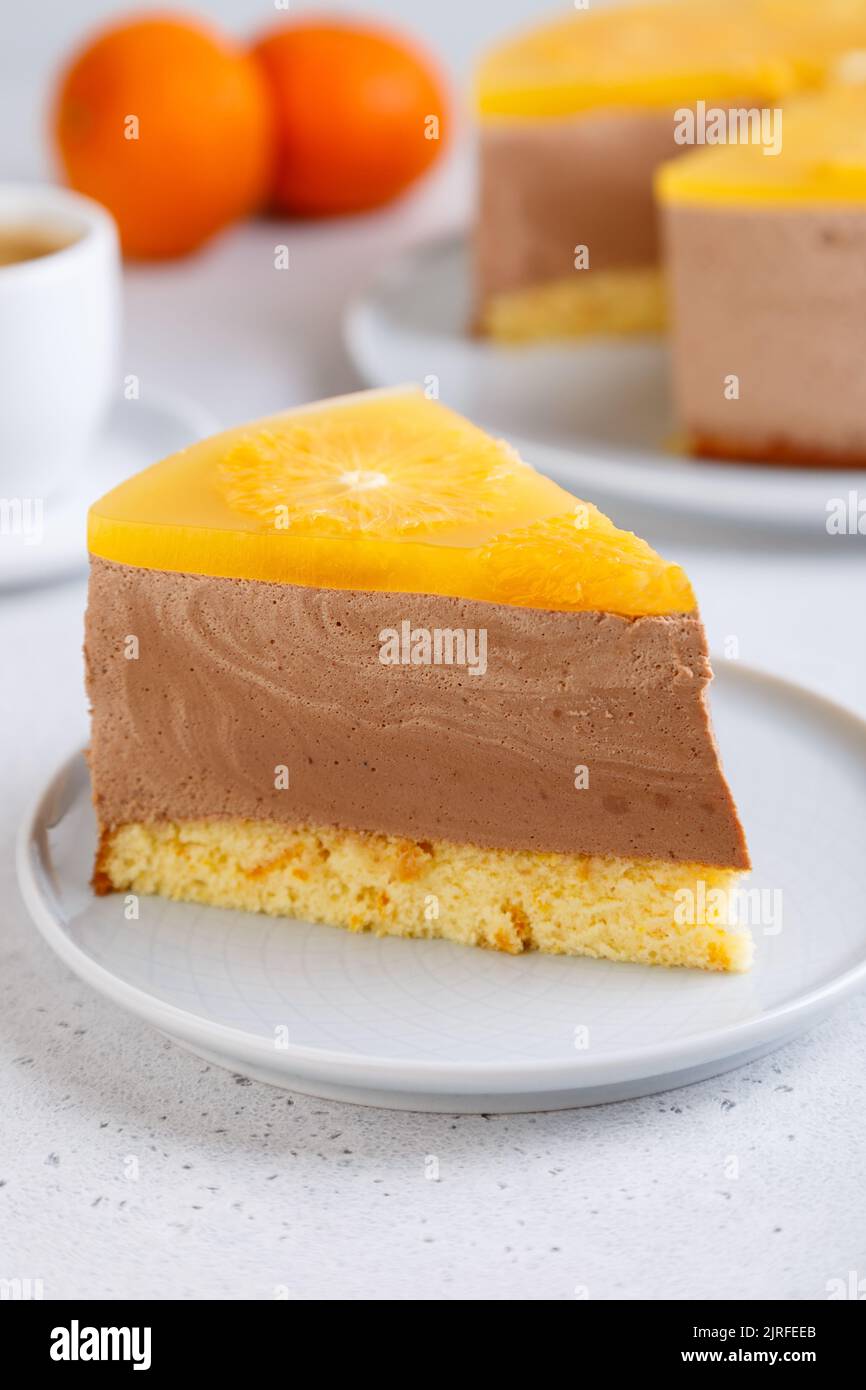 Schokoladen-Orange-Mousse-Kuchen mit Biskuitboden, Gelee und Orangenkreisen. Ein Stück hausgemachter Käsekuchen und eine Tasse Kaffee. Traditionelles Dessert Stockfoto