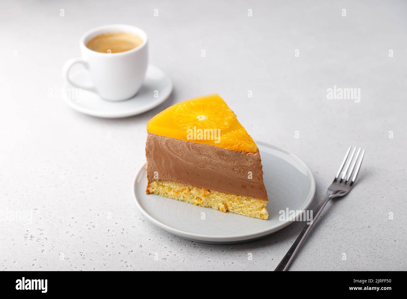 Schokoladen-Orange-Mousse-Kuchen mit Biskuitboden, Gelee und Orangenkreisen. Ein Stück hausgemachter Käsekuchen und eine Tasse Kaffee. Traditionelles Dessert Stockfoto