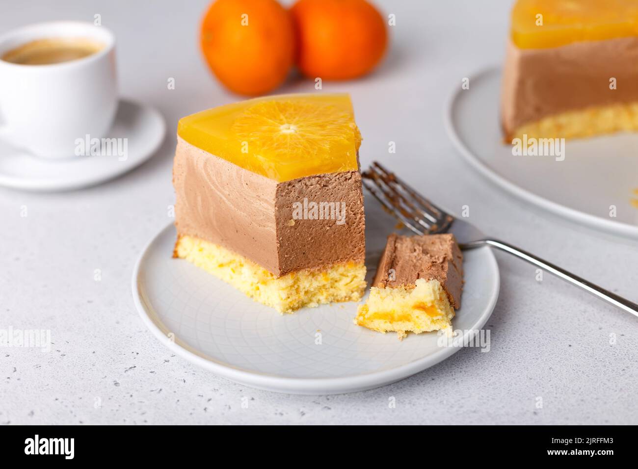 Schokoladen-Orange-Mousse-Kuchen mit Biskuitboden, Gelee und Orangenkreisen. Ein Stück hausgemachter Käsekuchen und eine Tasse Kaffee. Traditionelles Dessert Stockfoto