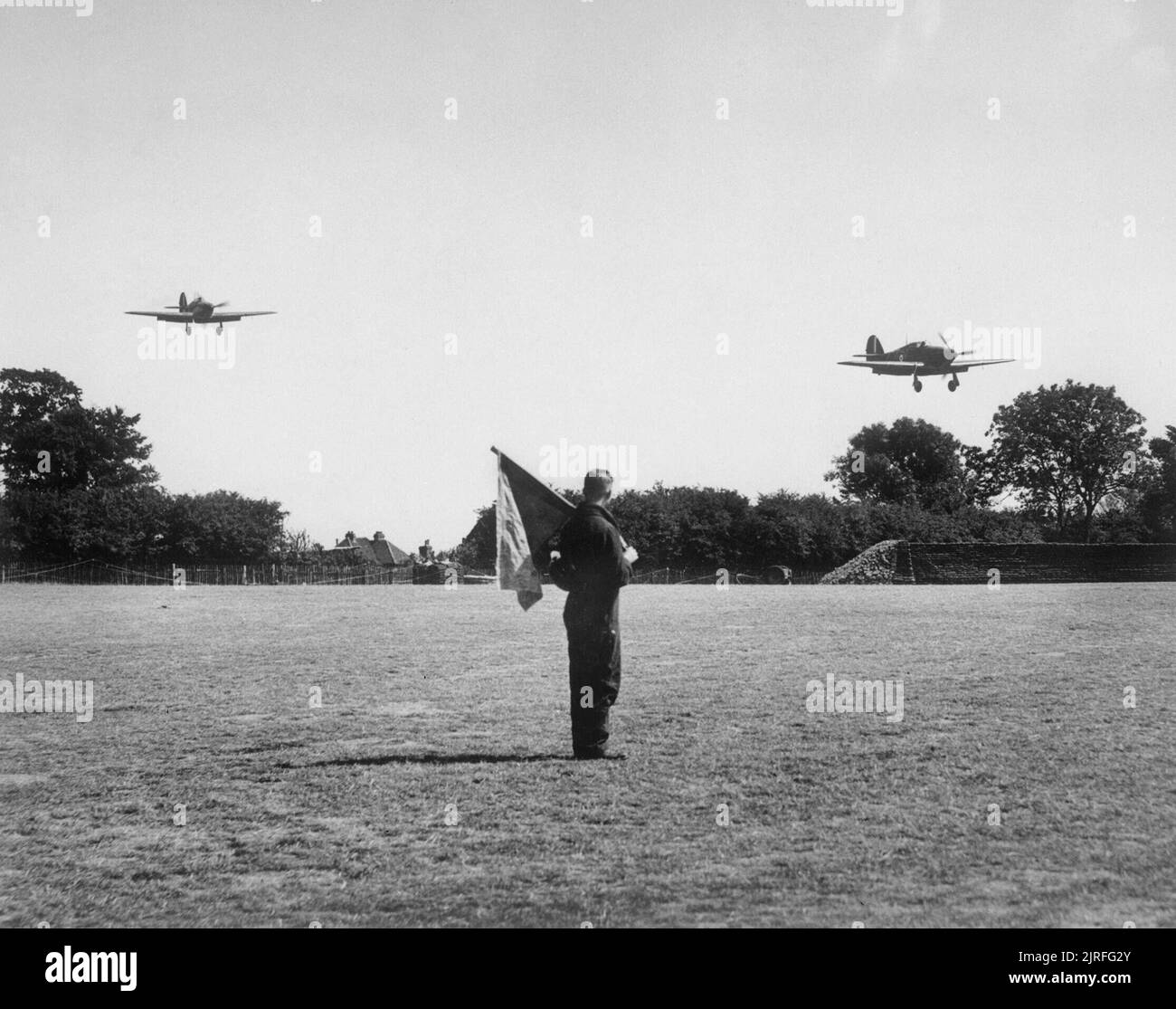 Die Schlacht um England zwei Hawker Hurricane Mk ist der Nr. 32 Squadron, Auftanken und Wiederbewaffnung in Biggin Hill zu landen, um einen Flieger mit einem Signalling Flag im Vordergrund aufgepaßt, August 1940. Stockfoto