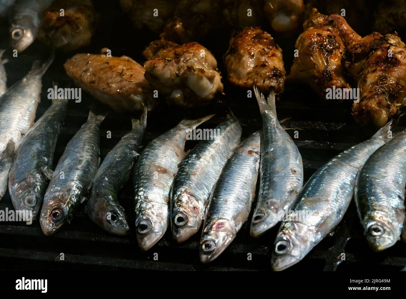 Blick von oben auf Sardinen und Hühnergerichte auf dem Grill Stockfoto