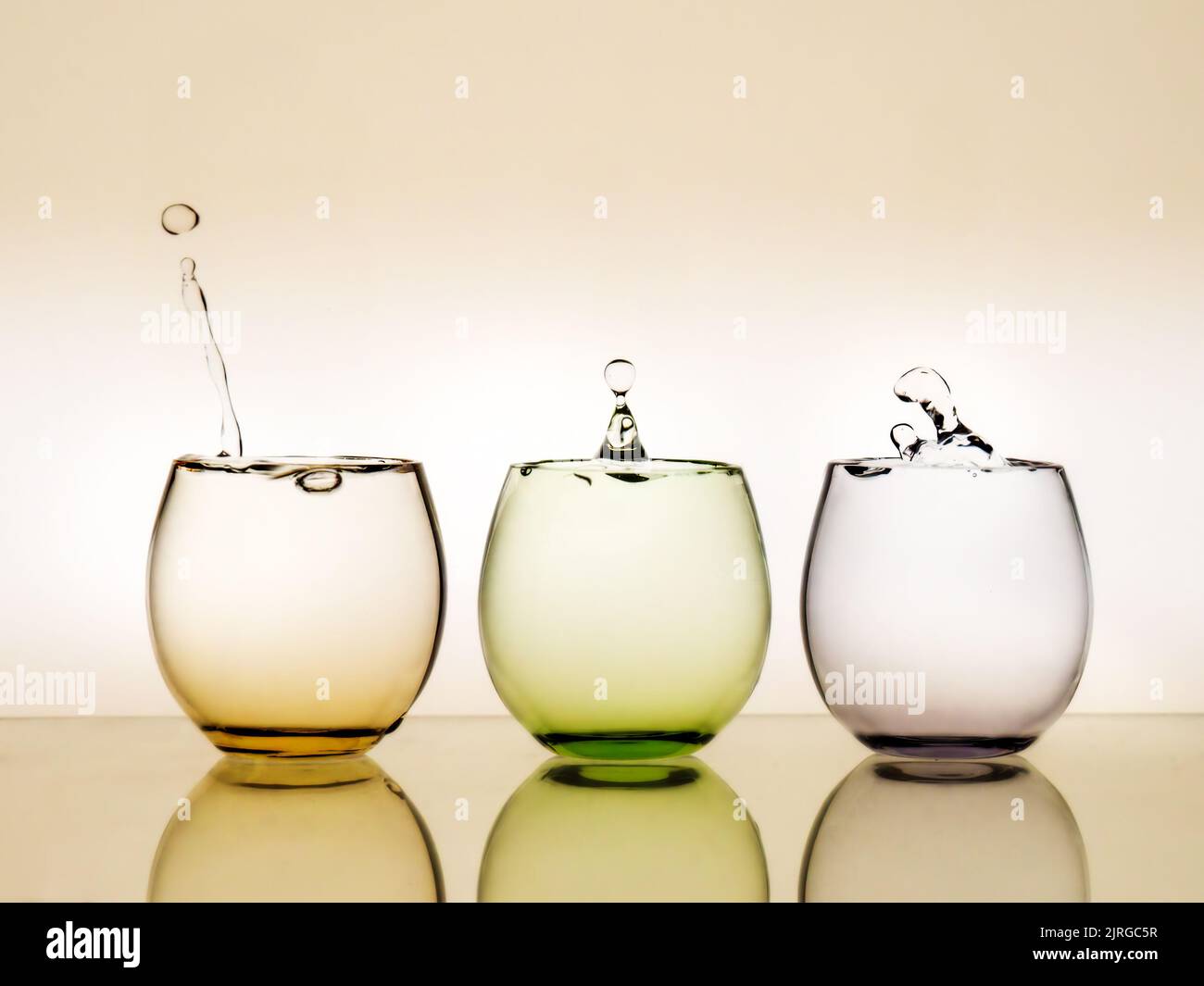Wasser fällt. Tropft in drei bunte Gläser. Stockfoto