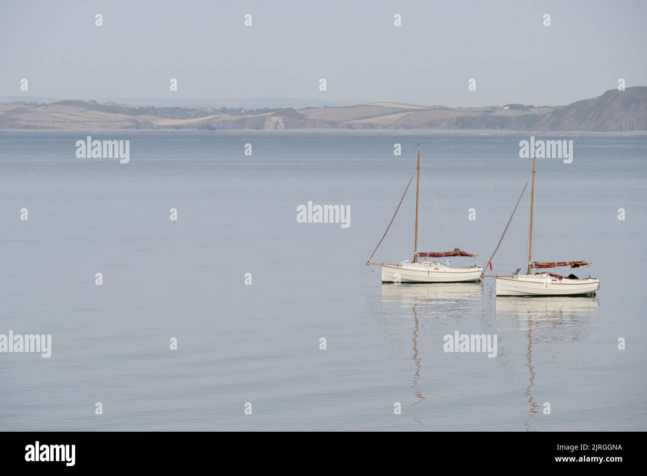 Zwei sehr ähnliche Segelboote auf ruhigem Wasser mit Reflexion. Ruhige Szene ruhige Landschaft. Stockfoto