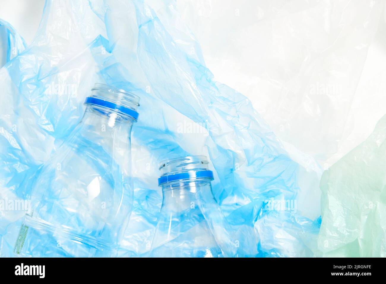 Transparente Einwegflaschen aus Kunststoff, grün und blau zerknittert Einweg-Plastiktüten. Konzepte: Nachhaltigkeit, Recycling, Umweltverschmutzung. Stockfoto