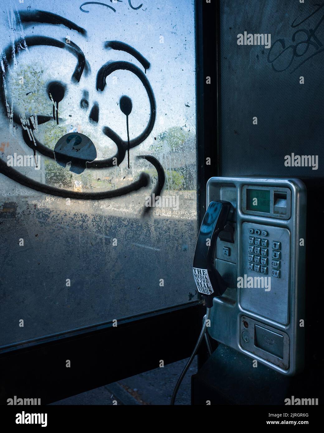 Mit Graffiti bedeckte Telefonzelle, mit Anti-Media-Covid-19-Virusnachricht auf dem Empfänger. Stockfoto