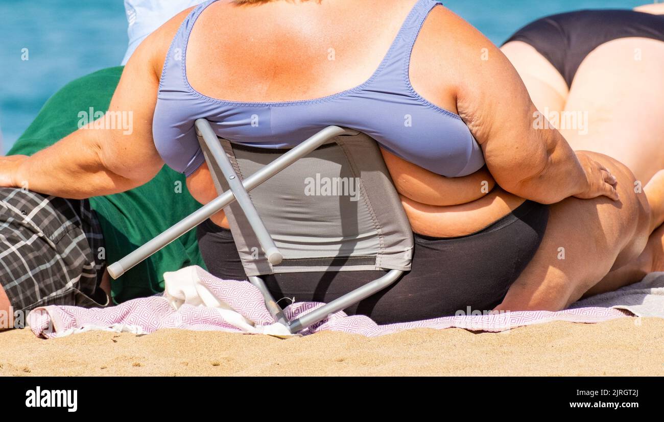 Übergewichtige Frau beim Sonnenbaden am Strand in Spanien Stockfoto