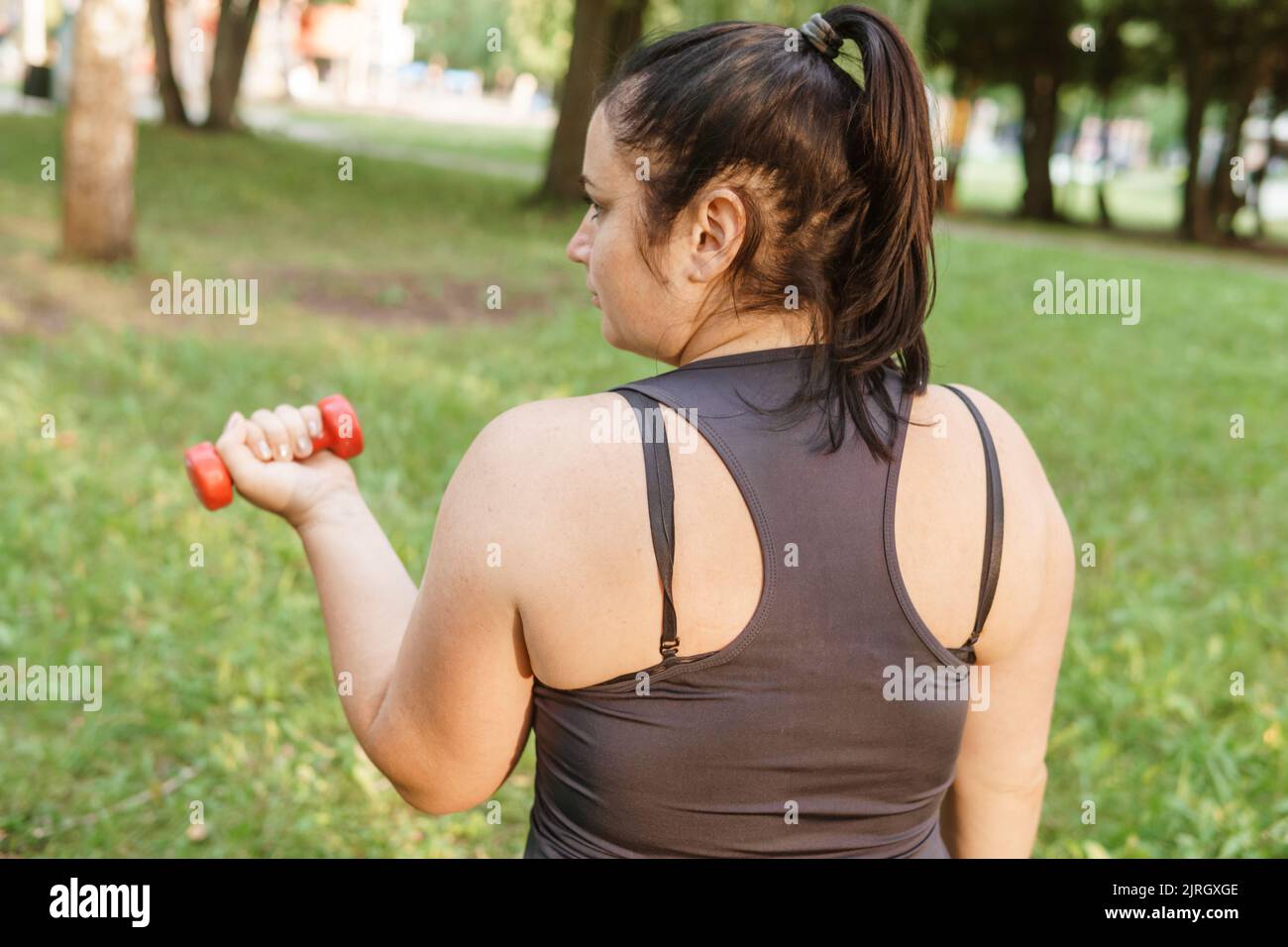 Eine charmante Brünette Frau plus-Größe Körper positiv praktiziert Sport in der Natur. Stockfoto
