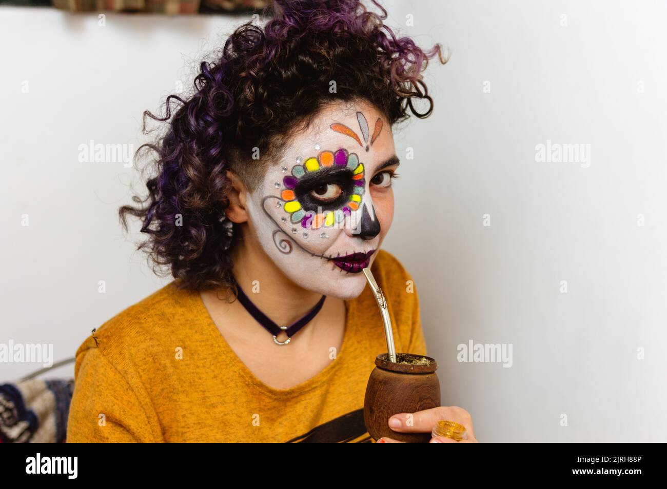 Porträt einer jungen lateinischen kaukasischen Frau mit La calavera catrina Make-up trinkende Mate Blick auf die Kamera, mexikanische Traditionen Konzept mit Kopie sp Stockfoto