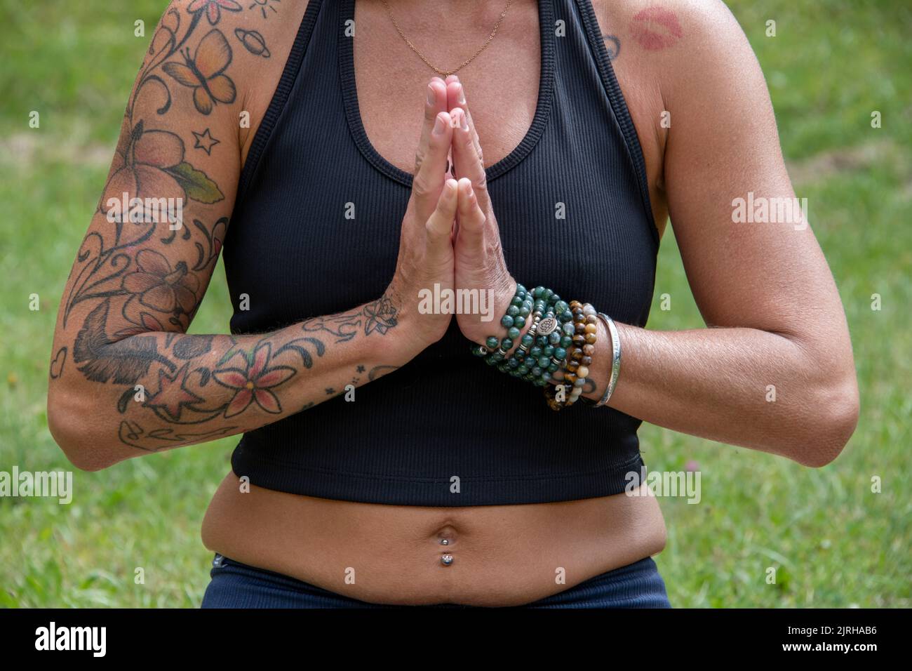 Körperteil einer europäischen Frau mit Tattoos und Piercing beim Yoga Stockfoto