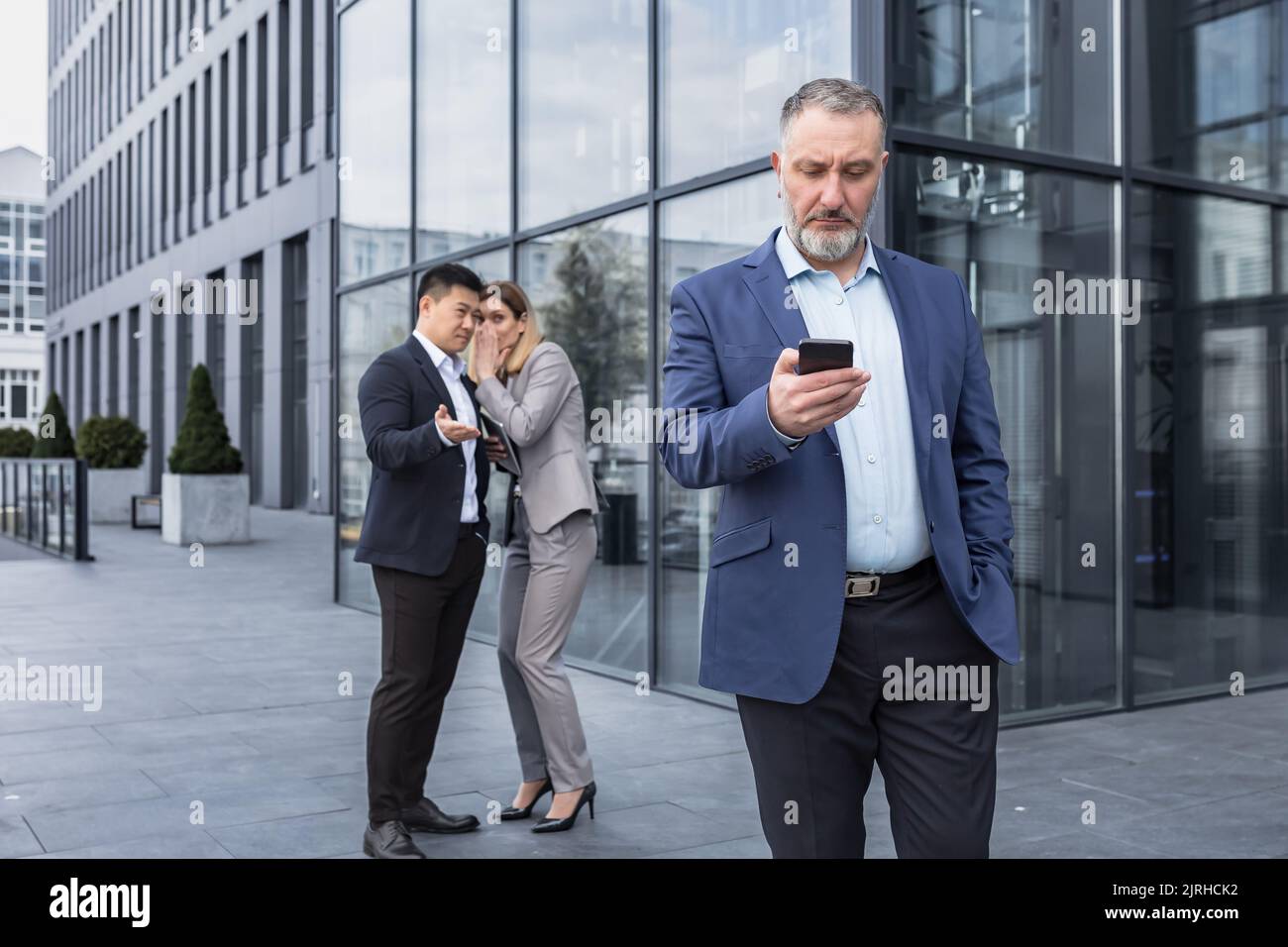 Zwei Kollegen klatschen über den Hintergrund hinter dem Chef. Arbeitskollege über Mobbing