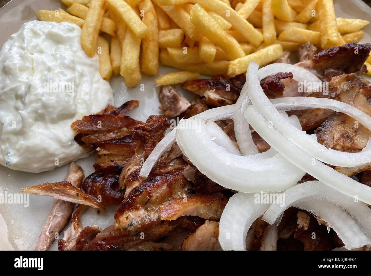 Nahaufnahme von isolierten bereit, griechische Schweinefleisch Gyros Platte mit Zwiebeln, pommes frites und tzatziki Dip zu essen Stockfoto