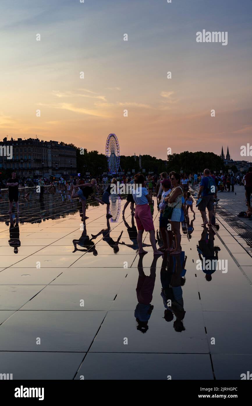 Bordeaux, Frankreich - Juli 17: Die Menschen bei Sonnenuntergang haben Spaß beim Spazieren im Wasserspiegelbrunnen am Place de la Bourse in Bordeaux, Aquitaine am 17. Juli, Stockfoto