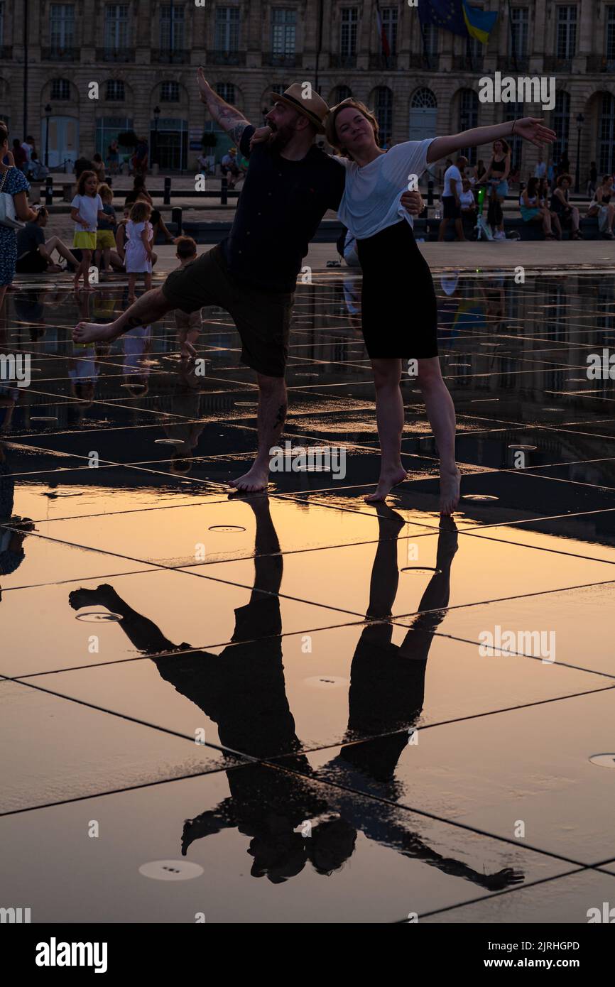 Bordeaux, Frankreich - Juli, 17: Ein paar Verliebte bei Sonnenuntergang haben Spaß beim Spazieren im Wasserspiegelbrunnen am Place de la Bourse in Bordeaux, Aquitanien Stockfoto
