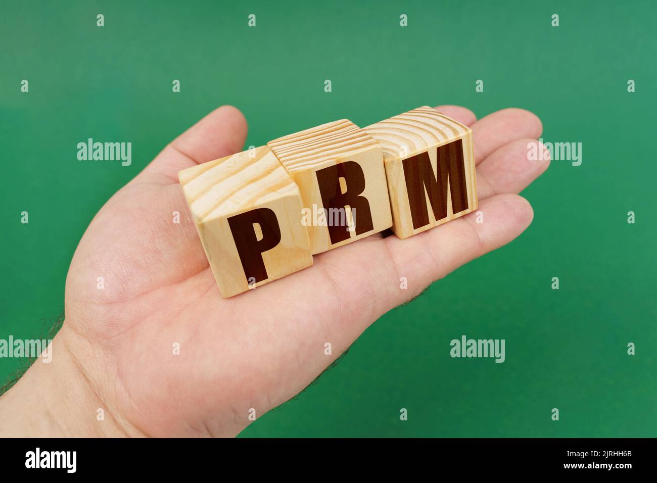 Geschäftskonzept. Auf einem grünen Hintergrund, in den Händen einer Person, Würfel mit der Aufschrift - PRM Stockfoto