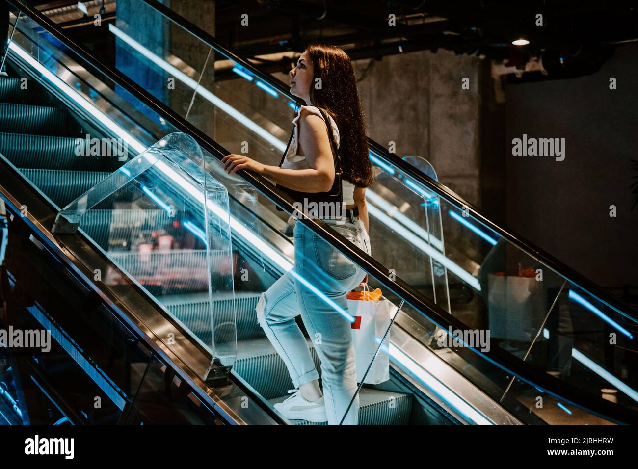 Junge Brünette Latina Attraktive Frau mit Einkaufstaschen auf der Rolltreppe im Fashion Store Mall. Stockfoto
