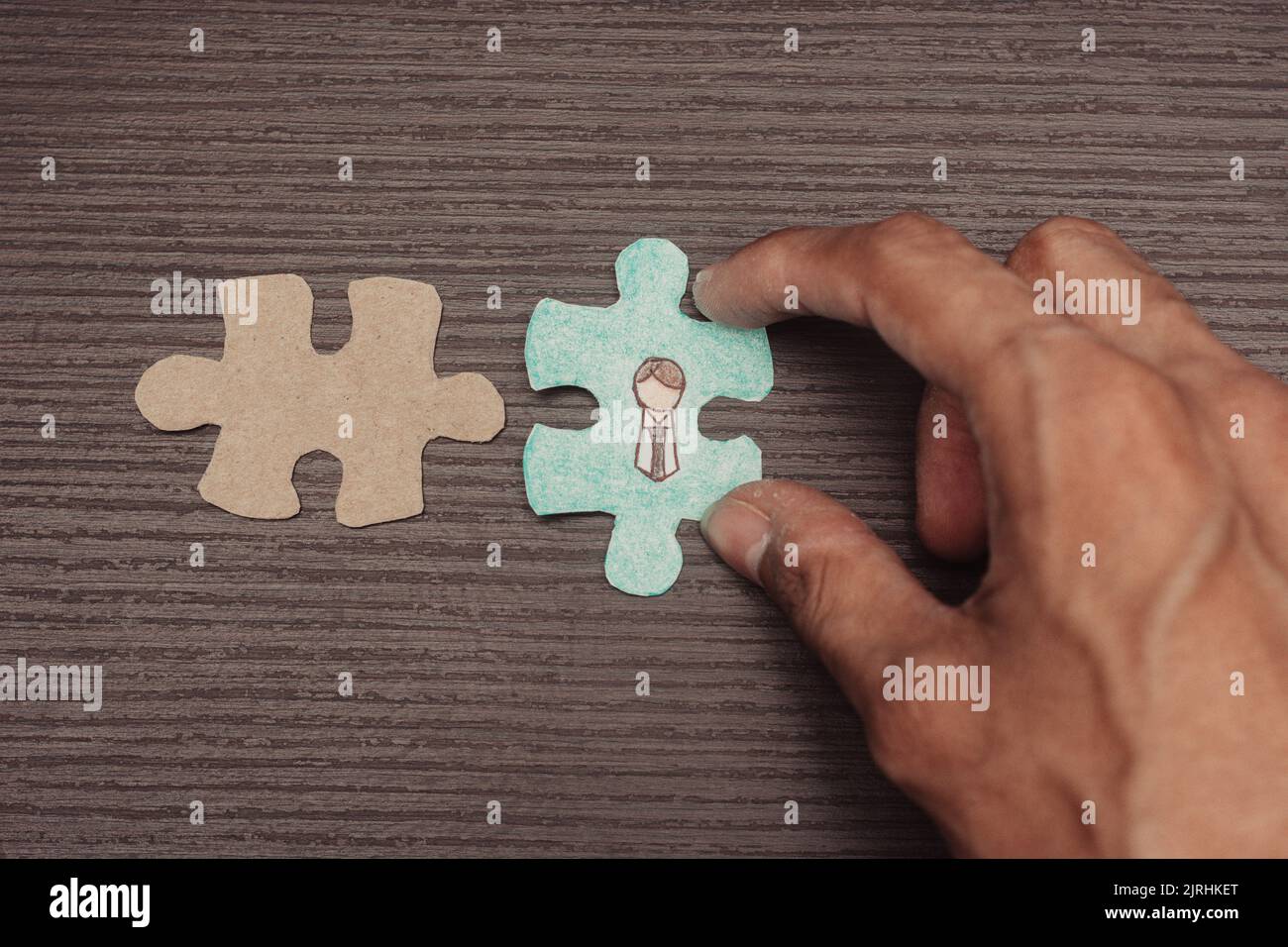 puzzleteil mit Figur des Büromitarbeiters. Leeres Puzzleteil. Ein Arbeitsteam bilden. Eine Hand führt einen Auswahlprozess durch. Geschäftskonzept und -Konzept Stockfoto