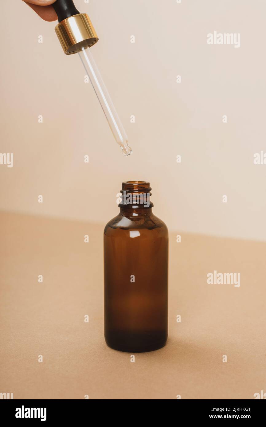 Braune Serumflasche aus Glas mit Pipette auf beigem Hintergrund. Selfcare, Anti-Aging-Kosmetik-Konzept. Nahaufnahme. Stockfoto