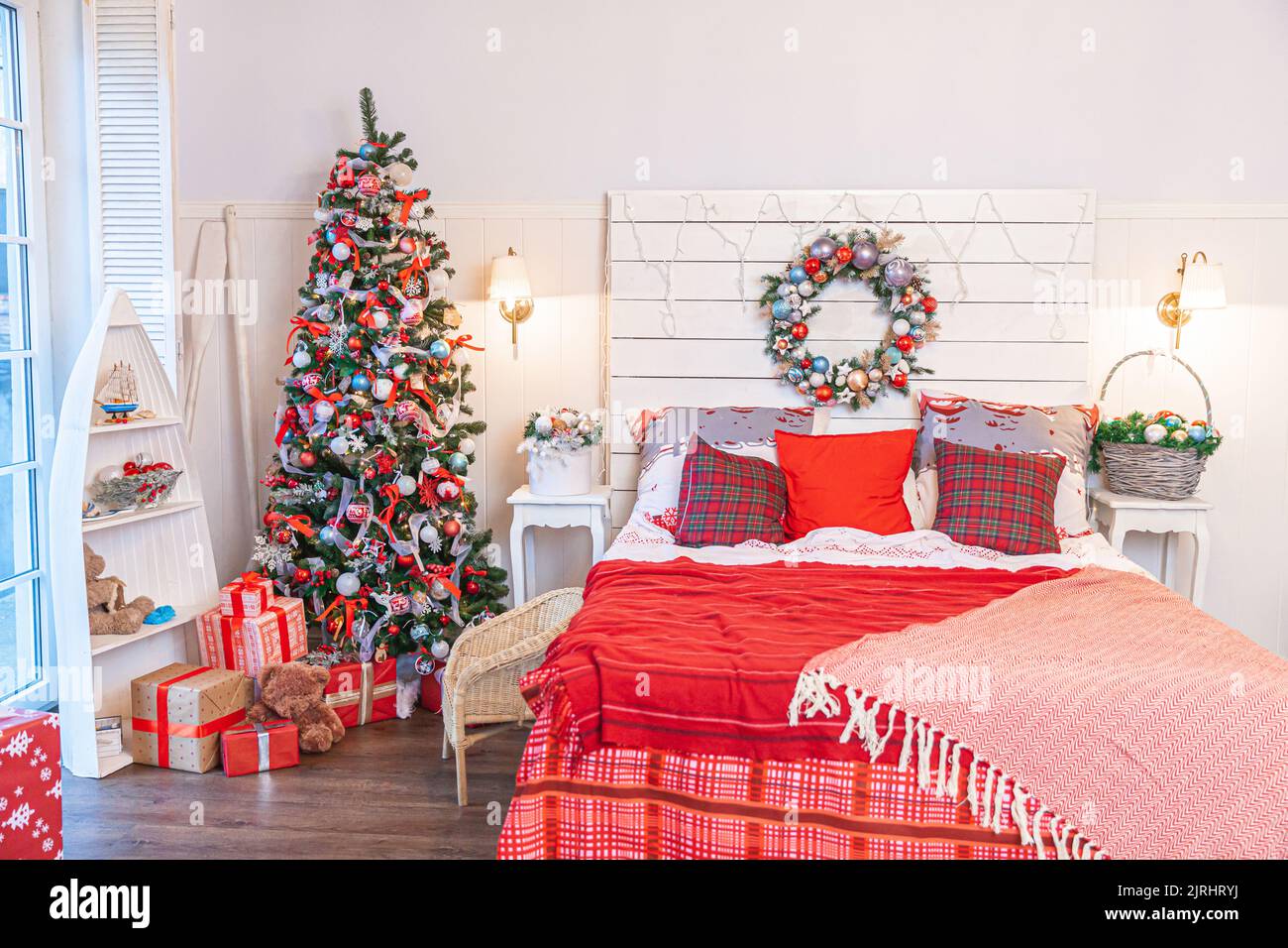 Klassischer Innenraum mit Weihnachtsbaum und traditionellen weißen roten Dekorationen. Modernes, sauberes, weißes, klassisches Innendesign-Apartment-Schlafzimmer. Heiligabend zu Hause. Minimalistisches Wohndesign Stockfoto