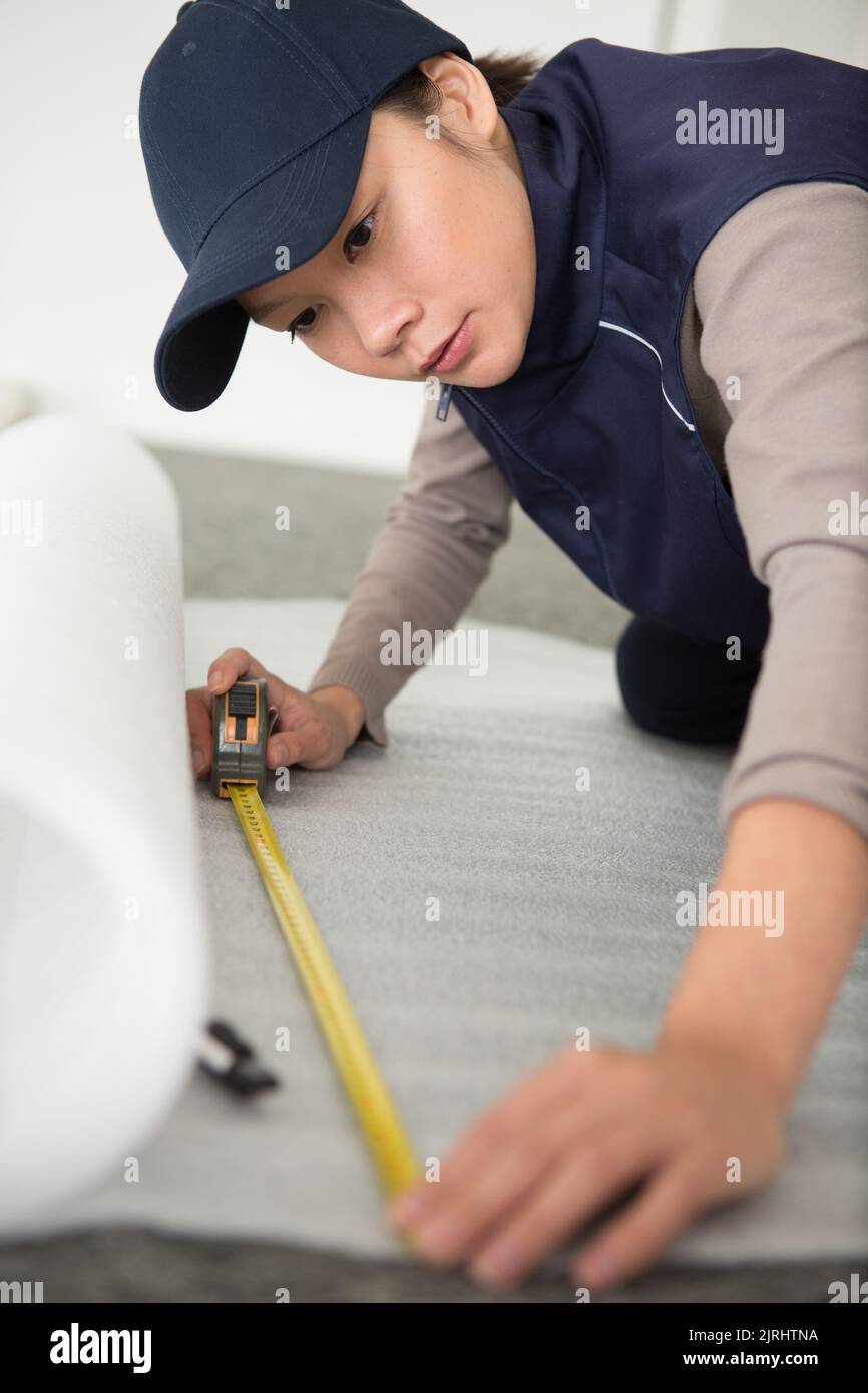 Frau misst ein Stück Tapetenrollen Stockfoto