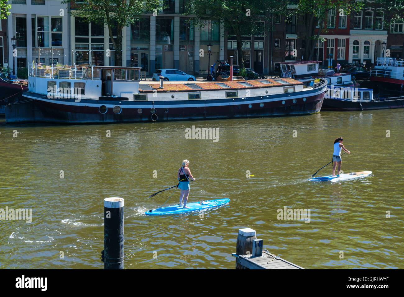 Amsterdam, Niederlande - 22. Juni 2022: Zwei Personen auf Paddelbrettern auf dem Amsterdamer Kanal Stockfoto