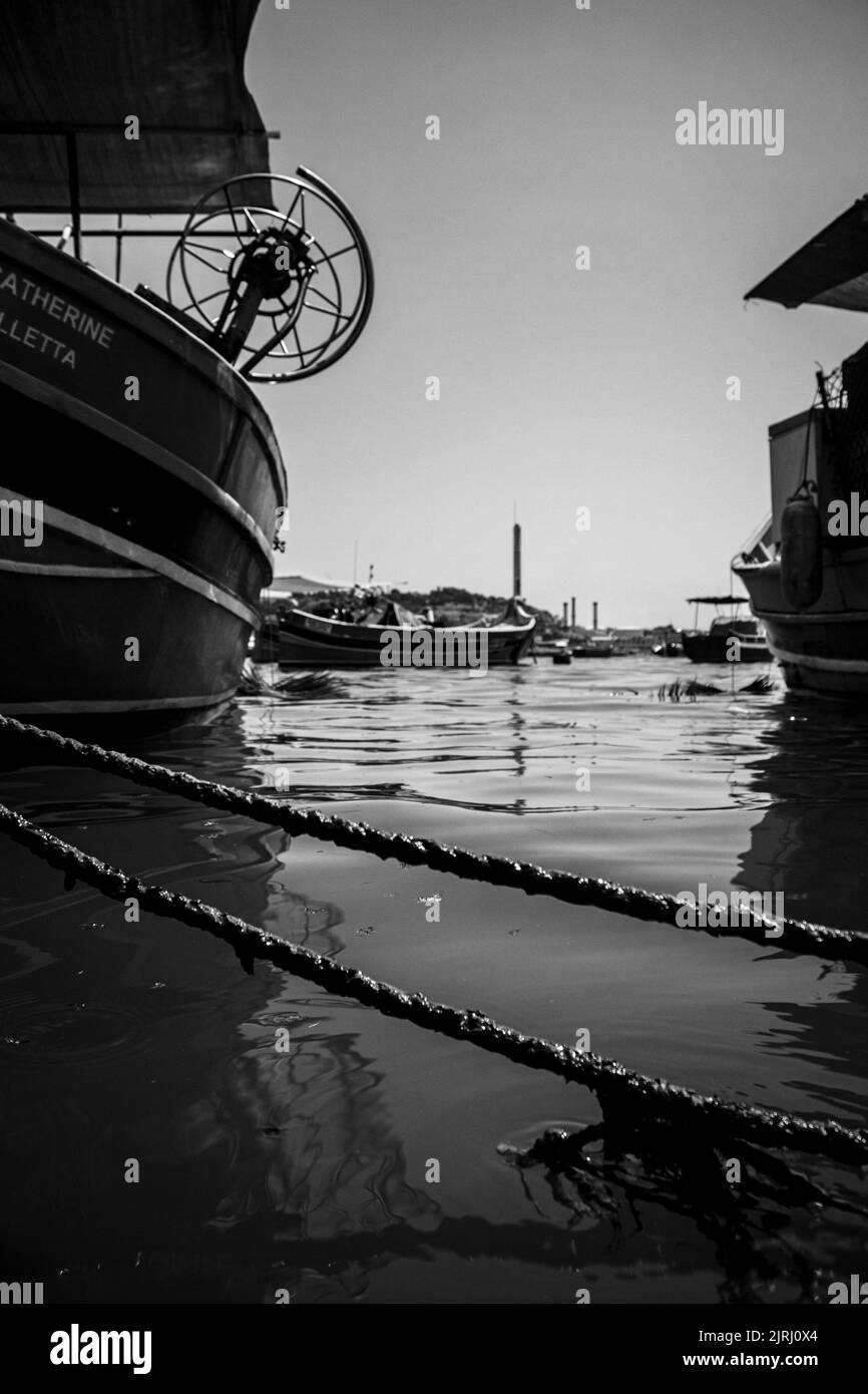 Eine vertikale Aufnahme von Wasser und Fragmenten von Schiffen auf einem Hafen in Graustufen Stockfoto