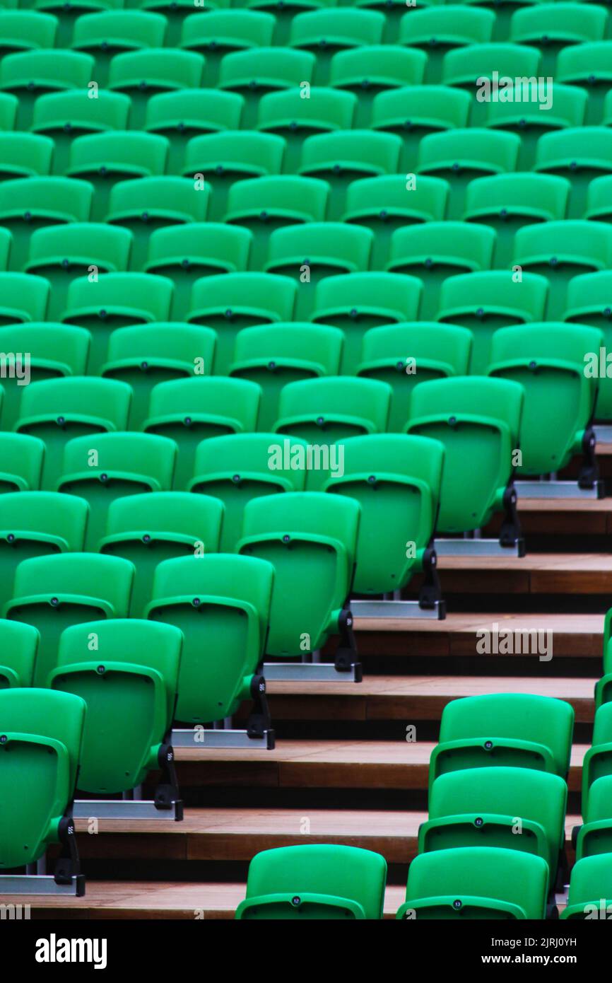 Eine vertikale Aufnahme von grünen Stadionsitzen und Staris Stockfoto