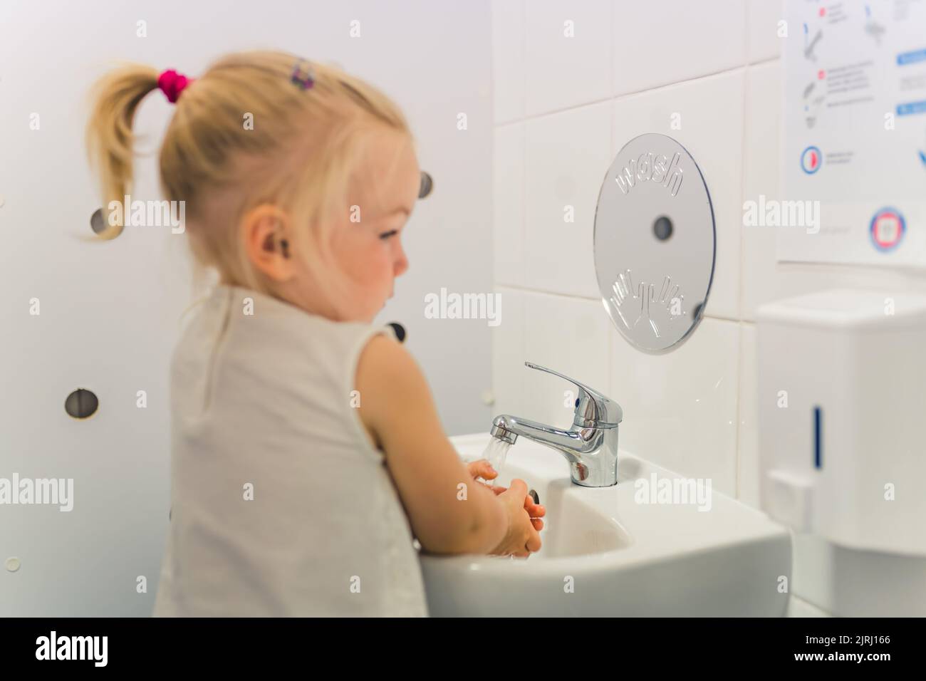 Kaukasische blonde Kleinkind Mädchen waschen ihre Hände mit Seife im Badezimmer nach Spielzeit in der Kinderkrippe. Konzept des frühen gesunden Hygiene-Lernens für Kinder Wellness. Hochwertige Fotos Stockfoto