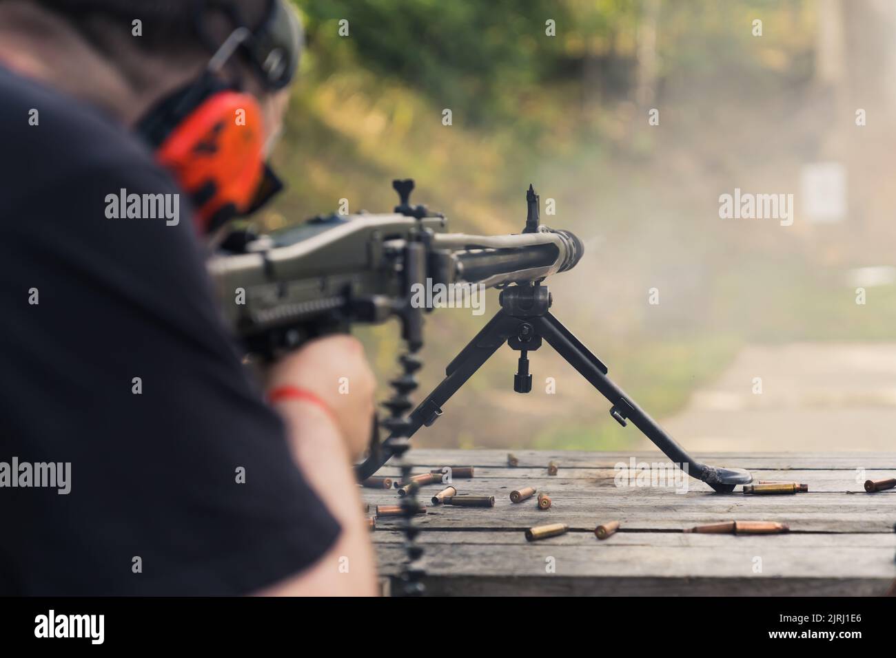 08.07.2022 Warschau, Polen unkenntliche kaukasische Person in roten Schutzohrhörern, die mit einem Maschinengewehr schießen. Wettbewerb auf Schießstand. Schusswaffenkonzept. Hochwertige Fotos Stockfoto