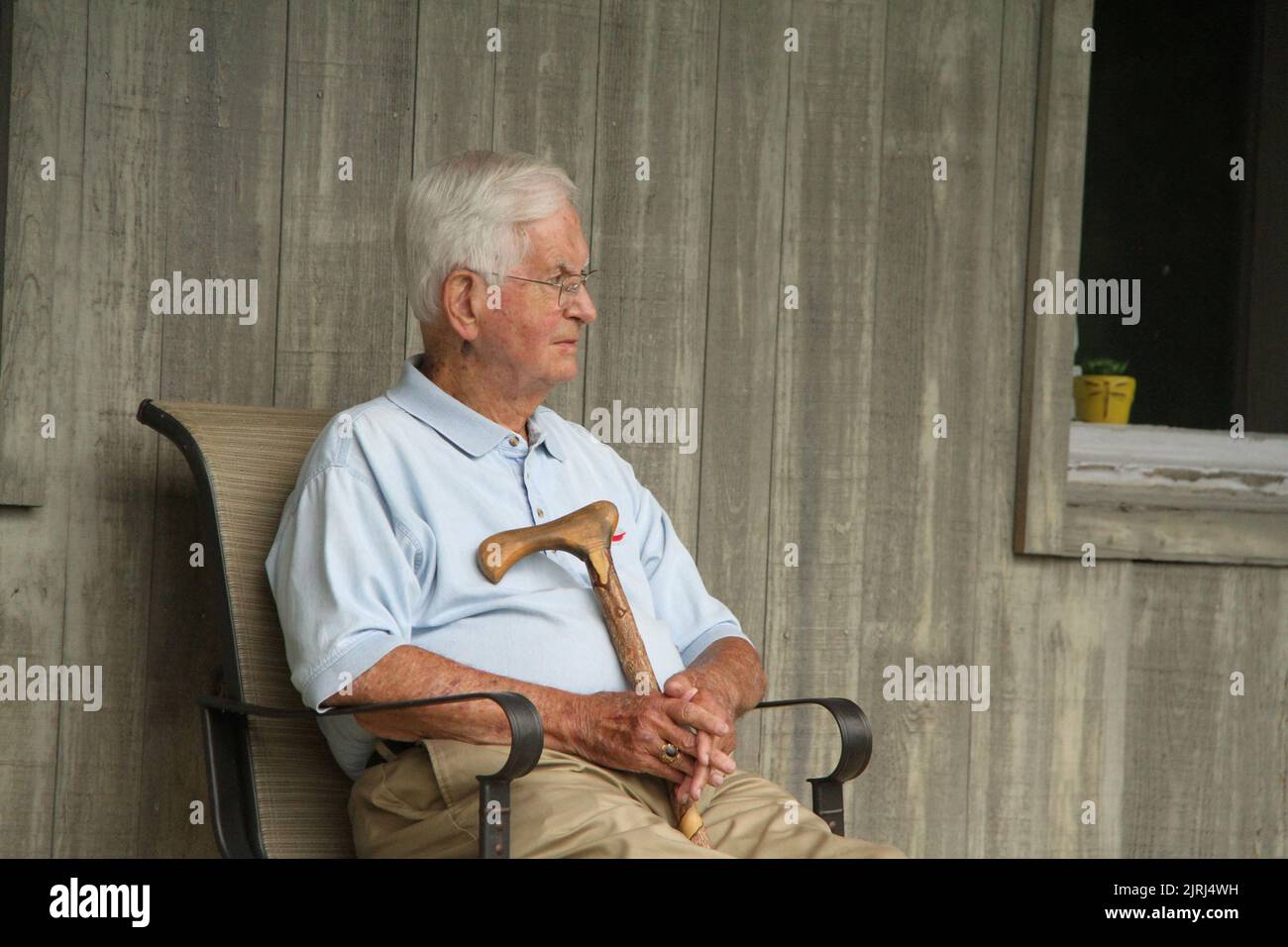 Älterer Mann mit Holzstock sitzend Stockfoto
