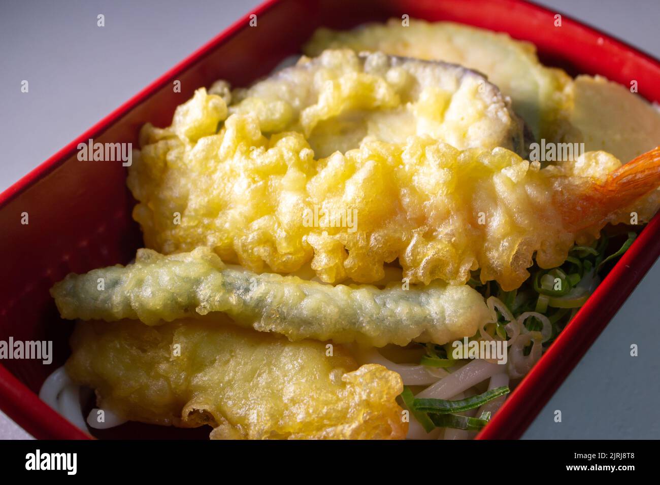 Nahaufnahme mit Udon Bento im Lebensmittelbehälter. Die Garnelen sind grüne Zwiebeln, japanisches Spiegelei (Tamagoyaki), GemüseTempura und Shrimp Tempura. Stockfoto