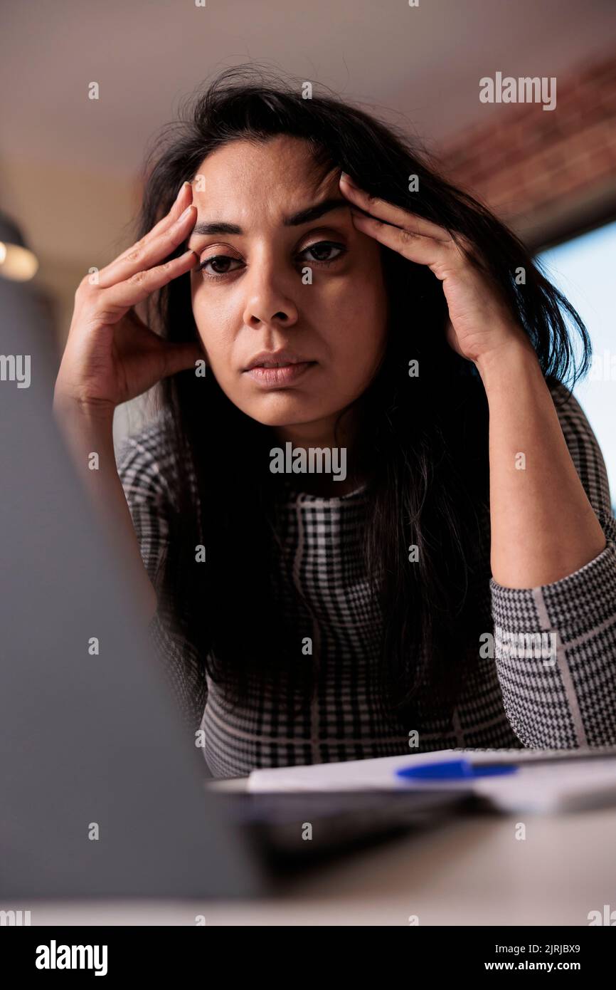 Erschöpfte Mitarbeiter sind frustriert über den Termin und arbeiten von zu Hause aus mit einem Laptop. Müde und verschlaf, gestresst über den Beruf und überfordert mit Kopfschmerzen. Burnout Schmerzen. Stockfoto