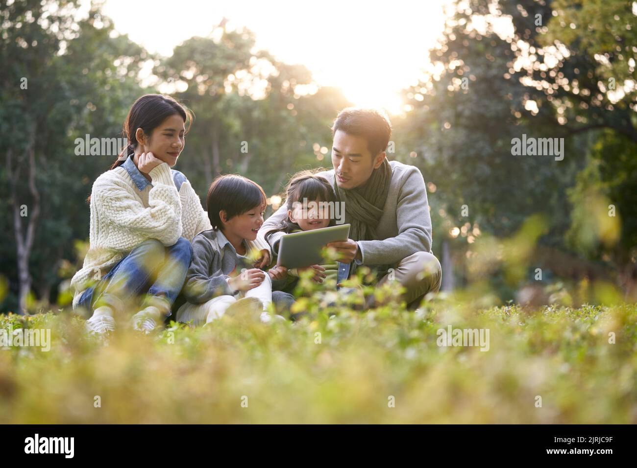 asiatische Familie mit zwei Kindern, die sich im Stadtpark entspannen Stockfoto