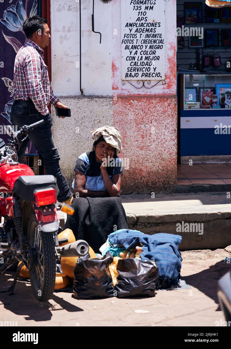 Eine alte arme Frau, die auf der Straße mit einigen Taschen vor ihr in San Cristobal, Chiapas, Mexiko, sitzt Stockfoto