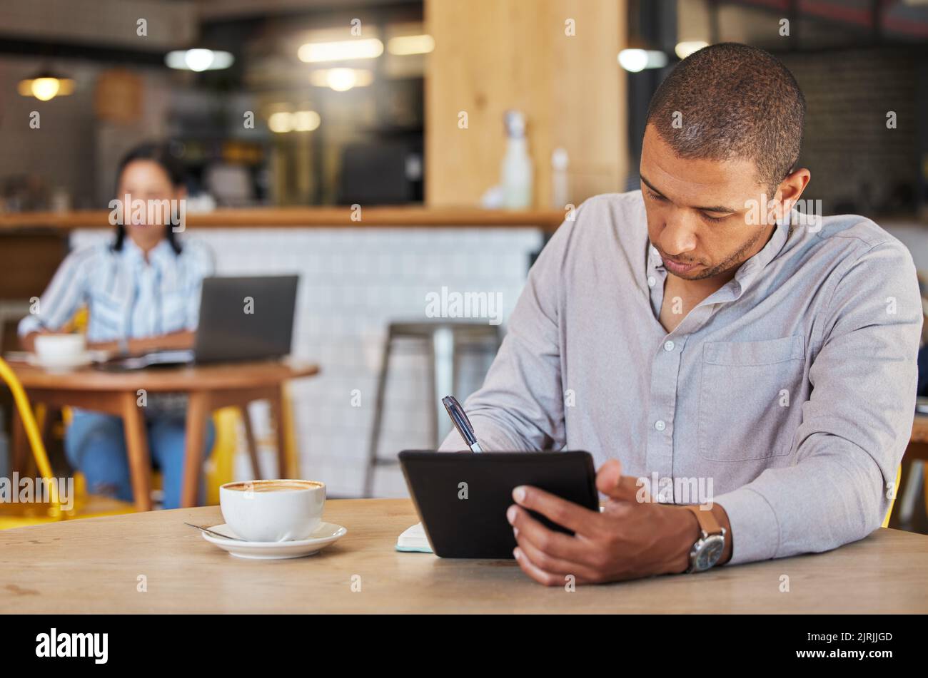 Freiberuflicher, geschäftlicher und Coffee Shop eines Mannes, der in einem Restaurant arbeitet und Remote-Arbeit für sein Startup leistet. Junger männlicher Unternehmer mit einem Tablet Stockfoto