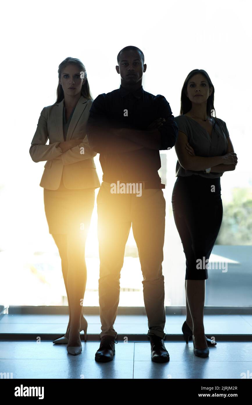 Bereit, neue Wege zu gehen. Silhouette einer Gruppe selbstbewusster Geschäftsleute, die in einem Büro zusammenstehen. Stockfoto